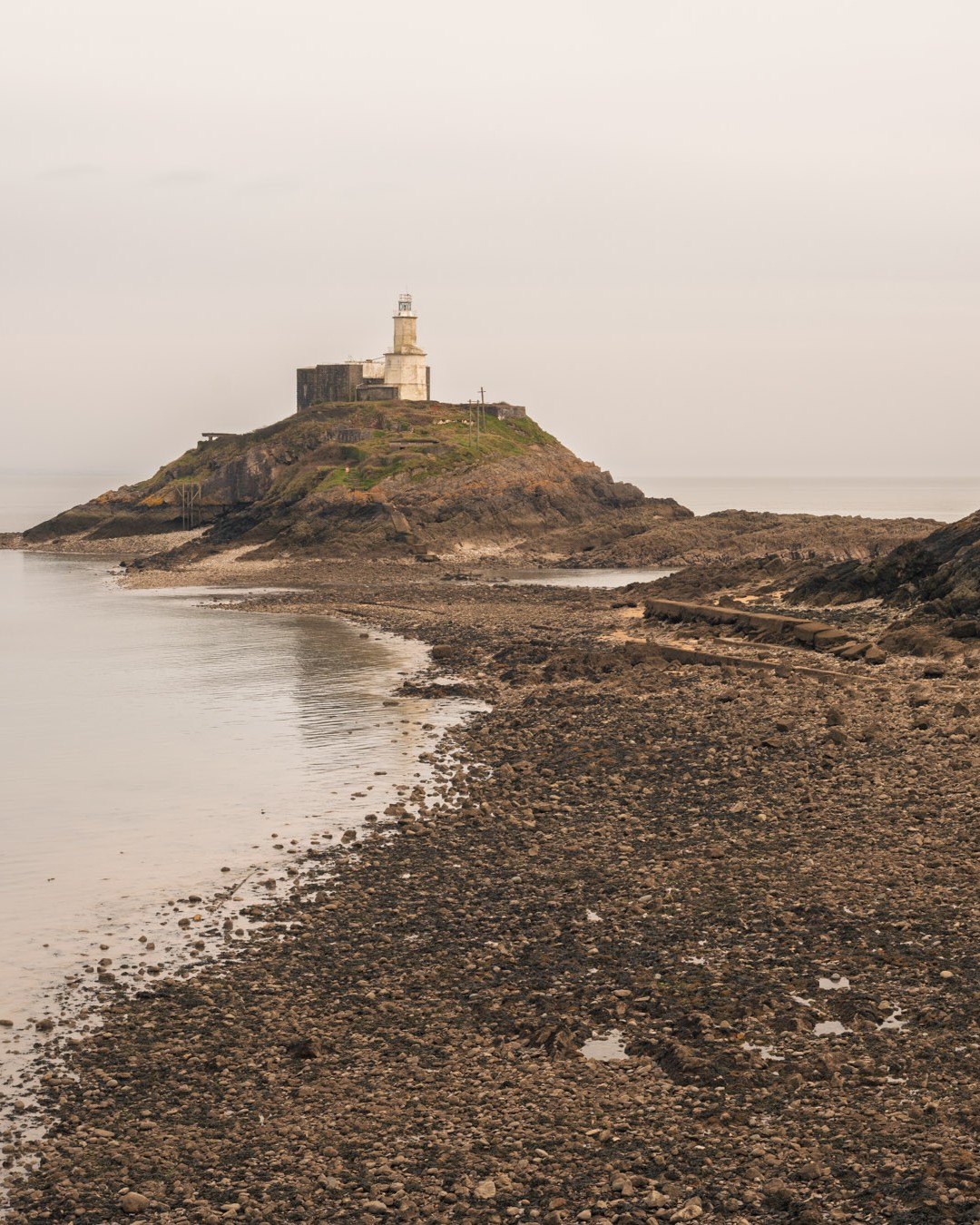 A rocky beach landscape with a lighthouse in the background