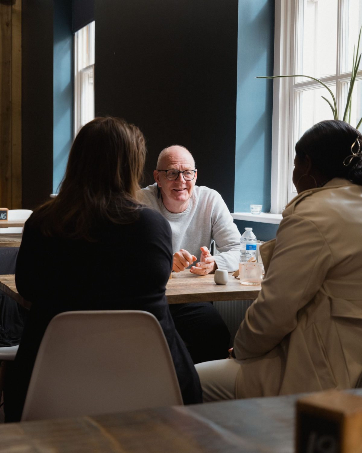 Three people sat around a table in a modern looking room talking