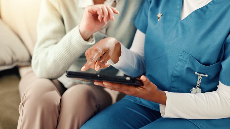 Tablet, hands and nurse with senior person on sofa for medical service, consulting and help. Retirement home, healthcare and caregiver with patient on tech for results, diagnosis or assisted living