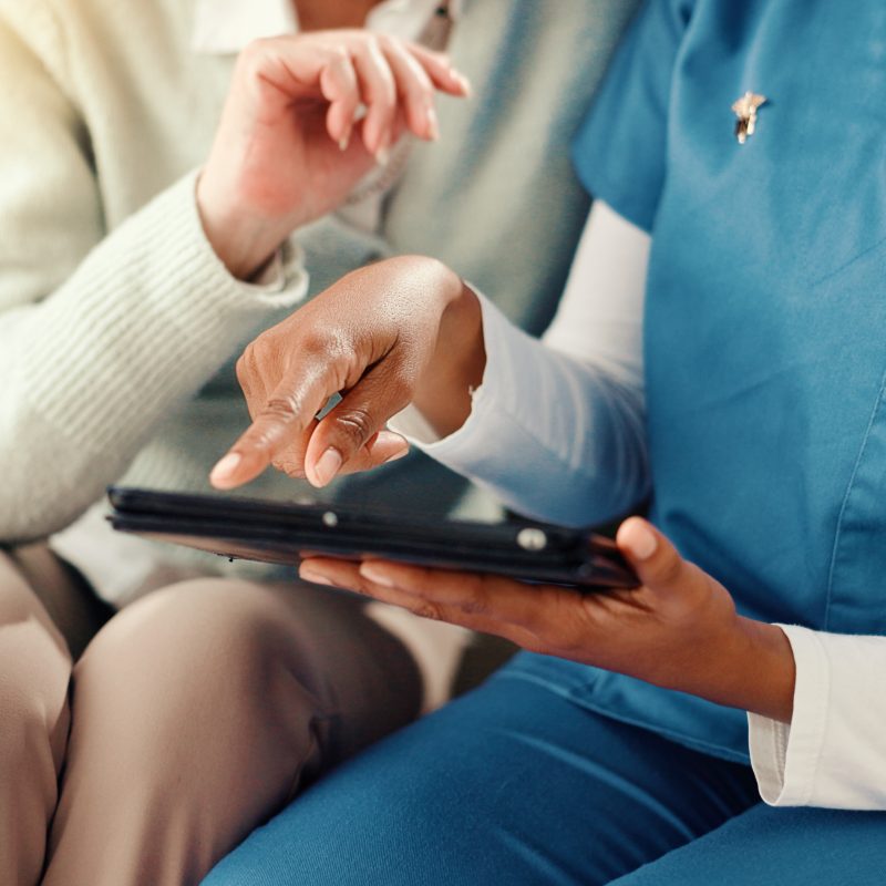 Tablet, hands and nurse with senior person on sofa for medical service, consulting and help. Retirement home, healthcare and caregiver with patient on tech for results, diagnosis or assisted living